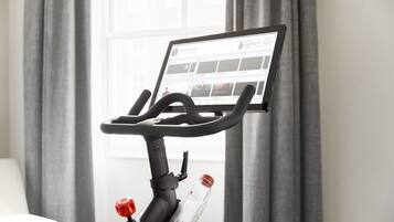 A stationary bike with a digital display screen, a water bottle holder, and a red knob.