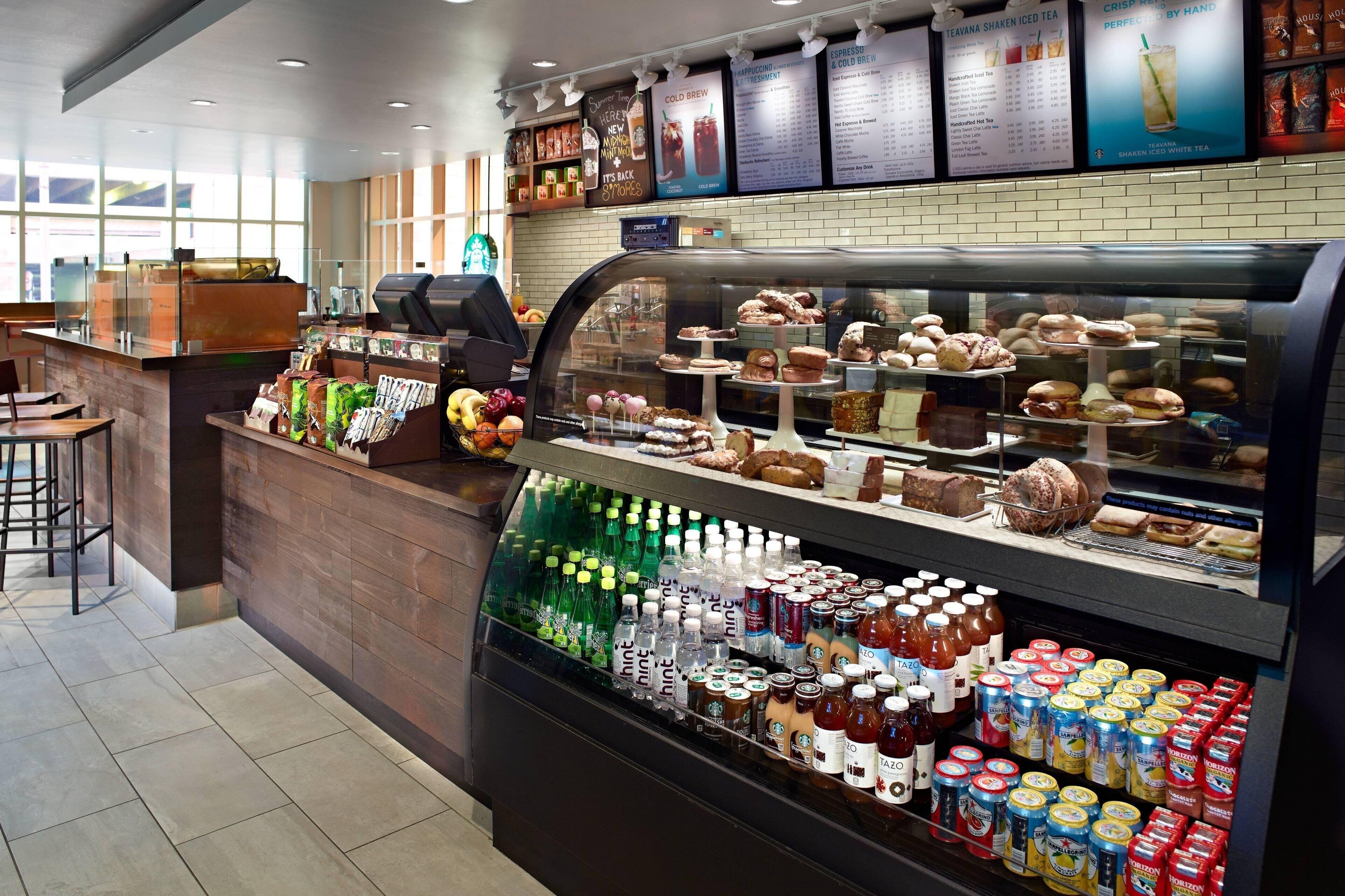 A coffee shop with a display case of pastries and a selection of bottled beverages.