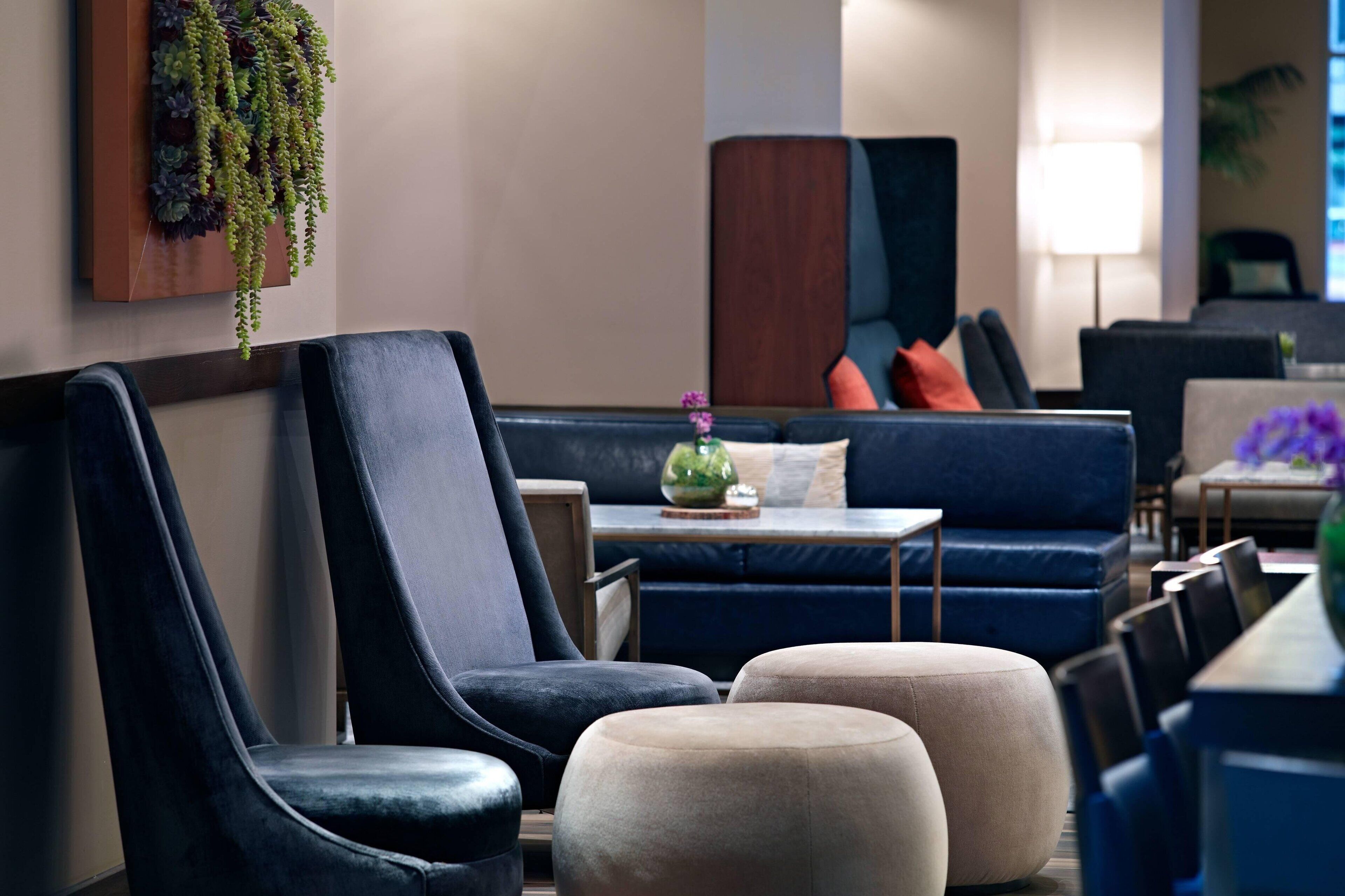 A modern lounge area with dark blue upholstered chairs, a sofa, and ottomans.