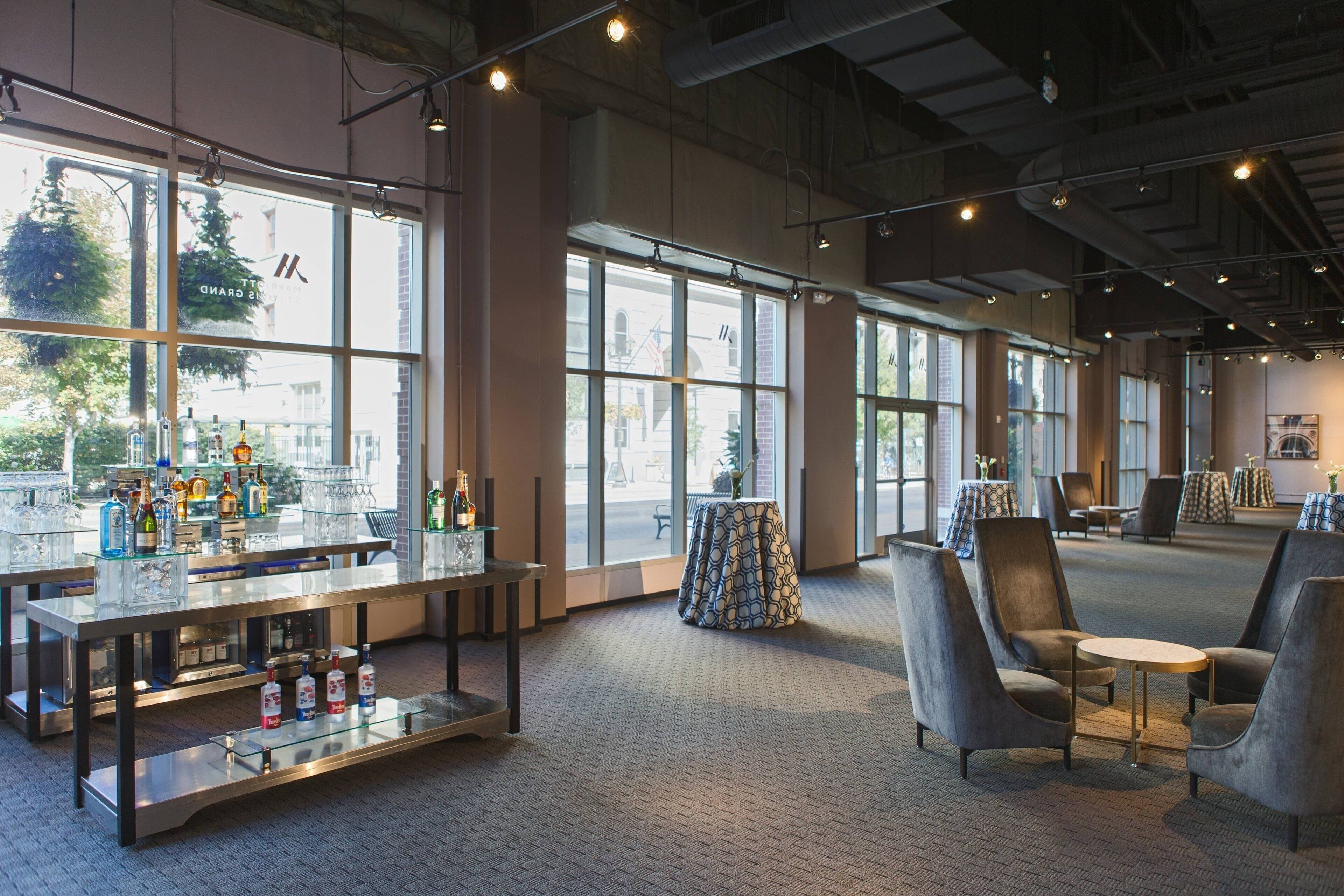 A spacious bar area with a bar counter, seating, and large windows offering views of the outside.