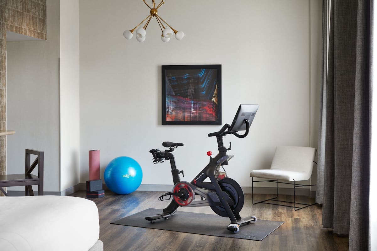 Una camera moderna con una cyclette, una palla da ginnastica blu e una sedia.