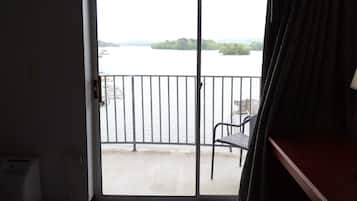 Une chambre avec vue sur un plan d’eau, un balcon avec une chaise et une porte donnant sur l’extérieur.