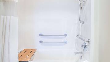Une baignoire blanche équipée de deux barres d’appui, d’un marchepied en bois et d’un pommeau de douche.