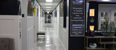 A hotel corridor with a signboard, a reception desk, and a bench.