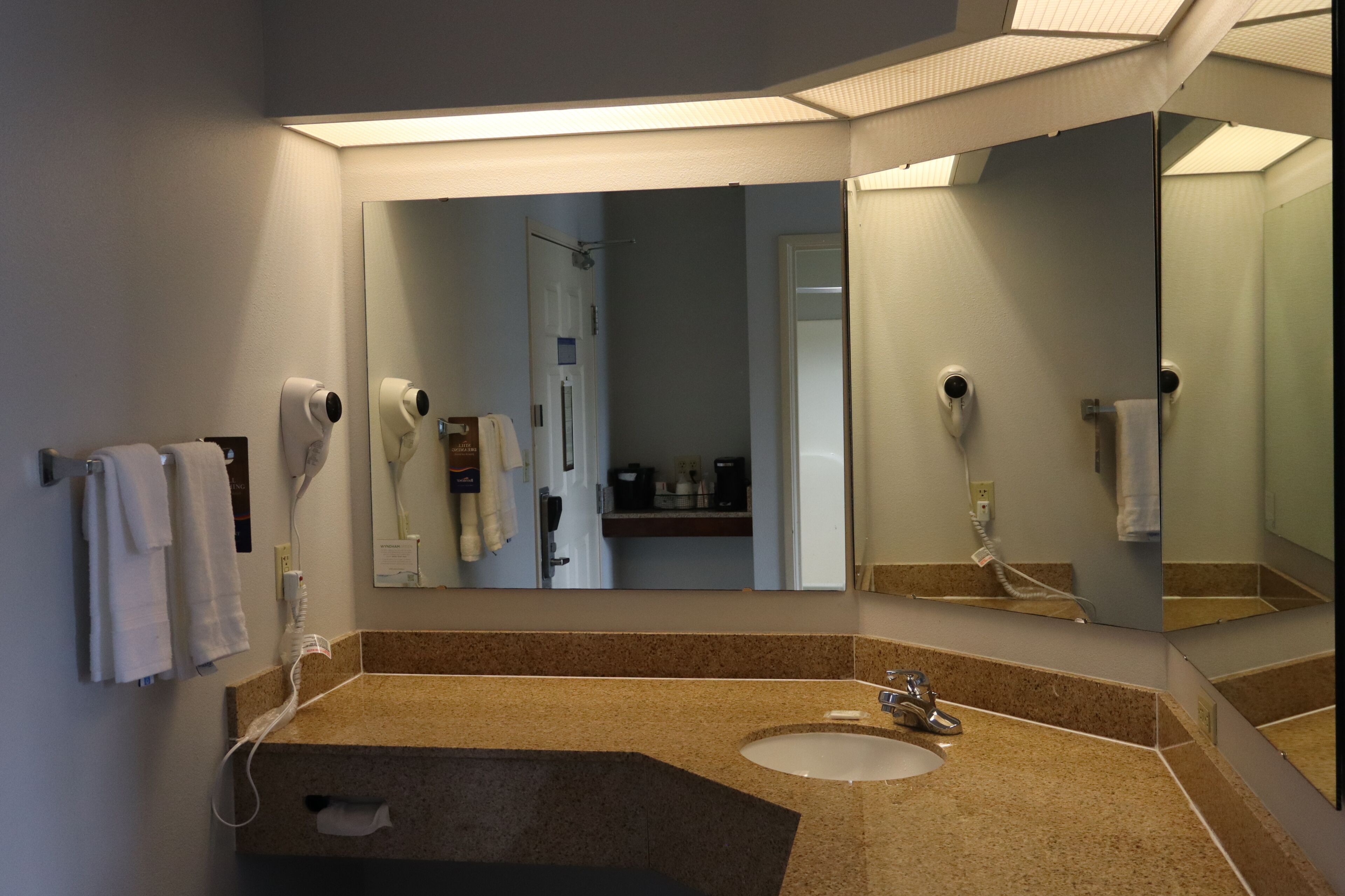 A bathroom with a sink, mirror, towel rack, and hairdryer.