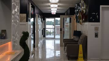 Hall d'albergo con reception, area d'attesa con sedie, cartello che segnala pavimento bagnato e indicazione di chiusura piscina.