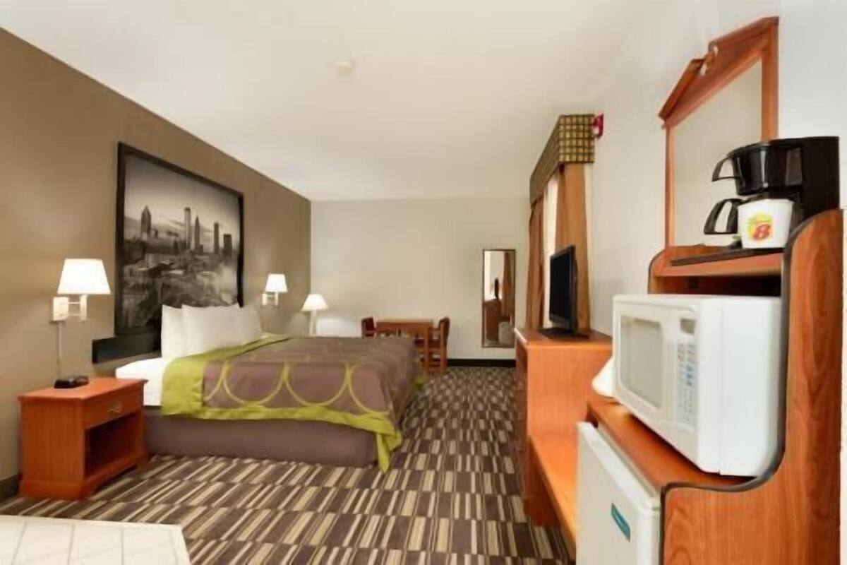 Una habitación de hotel con una cama, un escritorio, un televisor, un microondas y una cafetera.