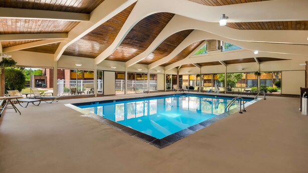 Piscina interna com teto de madeira e espreguiçadeiras.