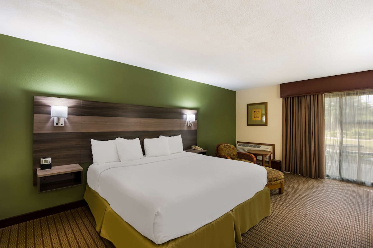 A hotel room with a large bed, bedside tables, a desk, and a chair.