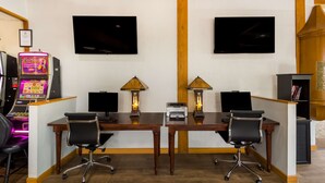 Quarto com duas mesas, cadeiras, um jukebox e duas televisões fixadas na parede.