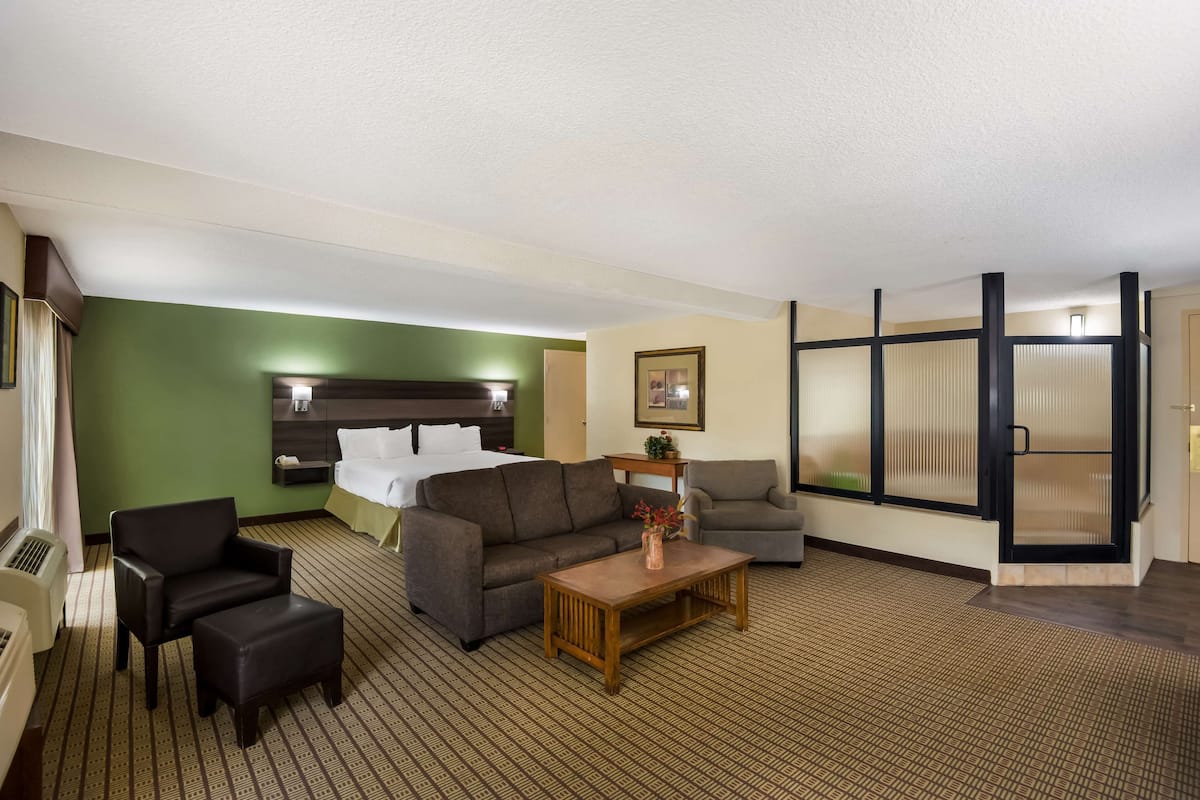 A hotel room with a bed, two sofas, a coffee table, and a large window.