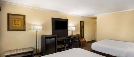Una habitación de hotel con cama, escritorio con silla, televisor, banco y dos lámparas.