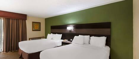 A hotel room with two beds, a nightstand, a lamp, and a framed picture on the wall.