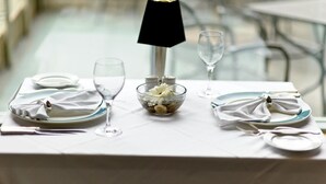 Ein Tisch ist gedeckt mit Tellern, Besteck, einer Nussmischung und einem Glas Wasser.