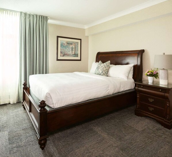 A neatly made bed with a wooden frame, a bedside table with a lamp, and a framed picture on the wall.
