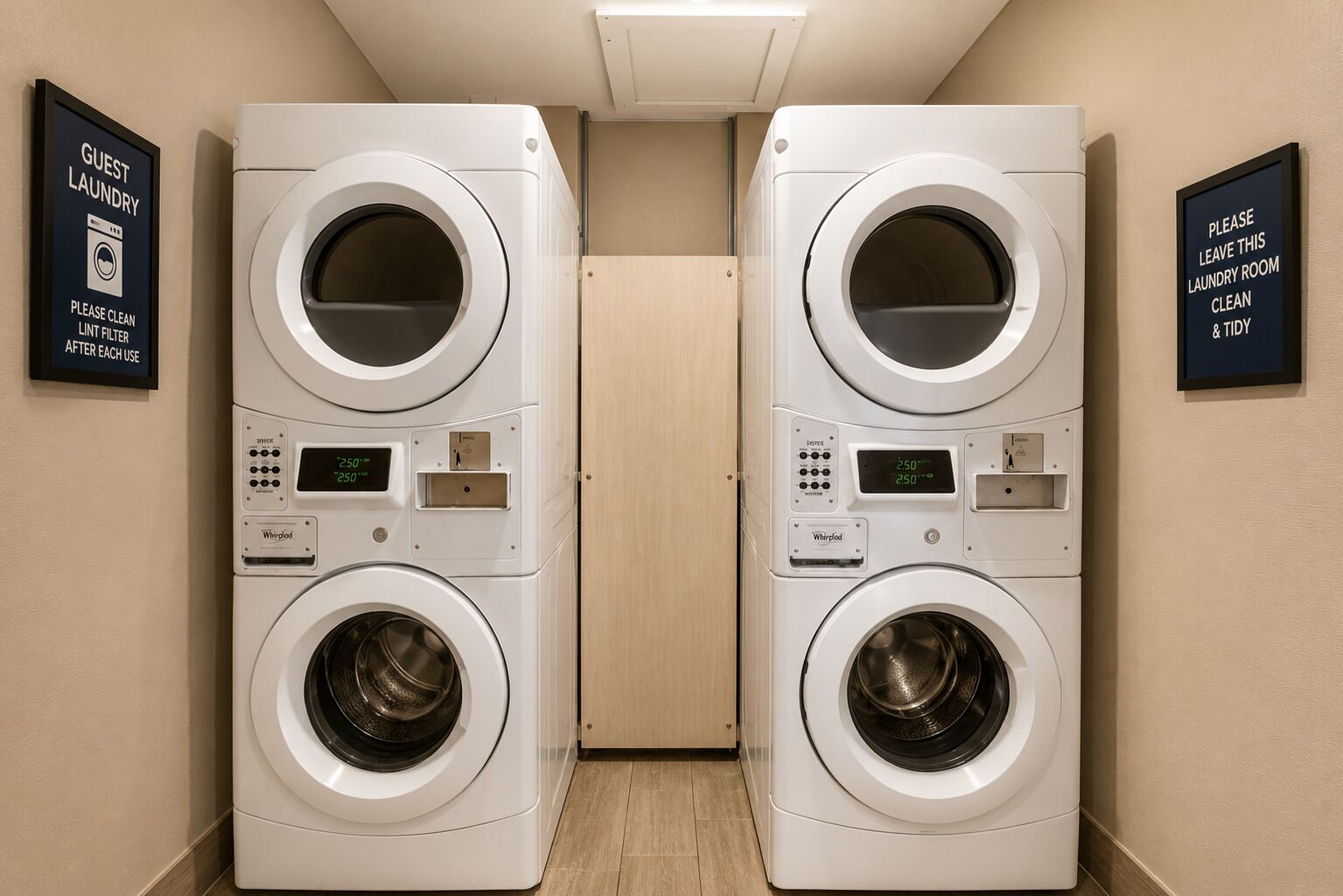 A hotel laundry room with two Whirlpool washers and dryers, a lint filter sign, and a cleanliness reminder sign.