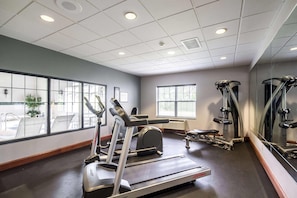 Une salle de sport équipée de tapis de course, d’un banc et d’appareils de musculation.