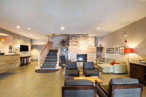 Amplia sala de estar con escalera, chimenea, un conjunto de sofás y televisor.