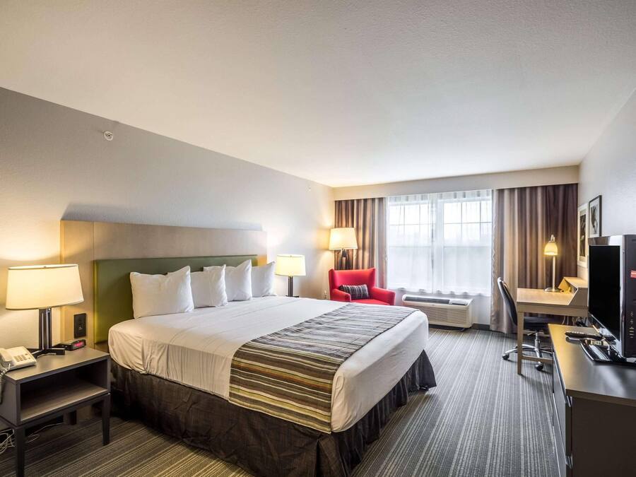Een hotelkamer met een bed, bureau, televisie en stoel.