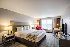 Une chambre d’hôtel avec un lit, un bureau, une télévision et une chaise.