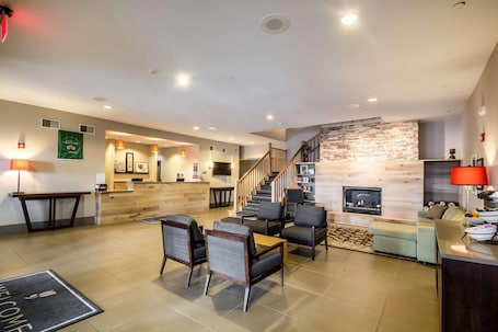 A hotel lobby with a reception desk, seating area, staircase, fireplace, and a wall-mounted television.. Country Inn & Suites by Radisson, Fond du Lac, WI