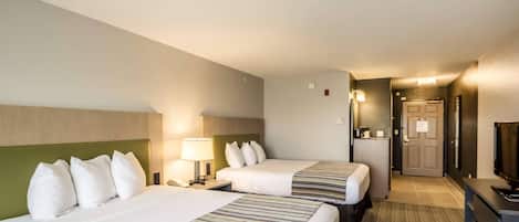 A hotel room with two beds, a desk, a chair, a TV, and a door leading to a hallway.
