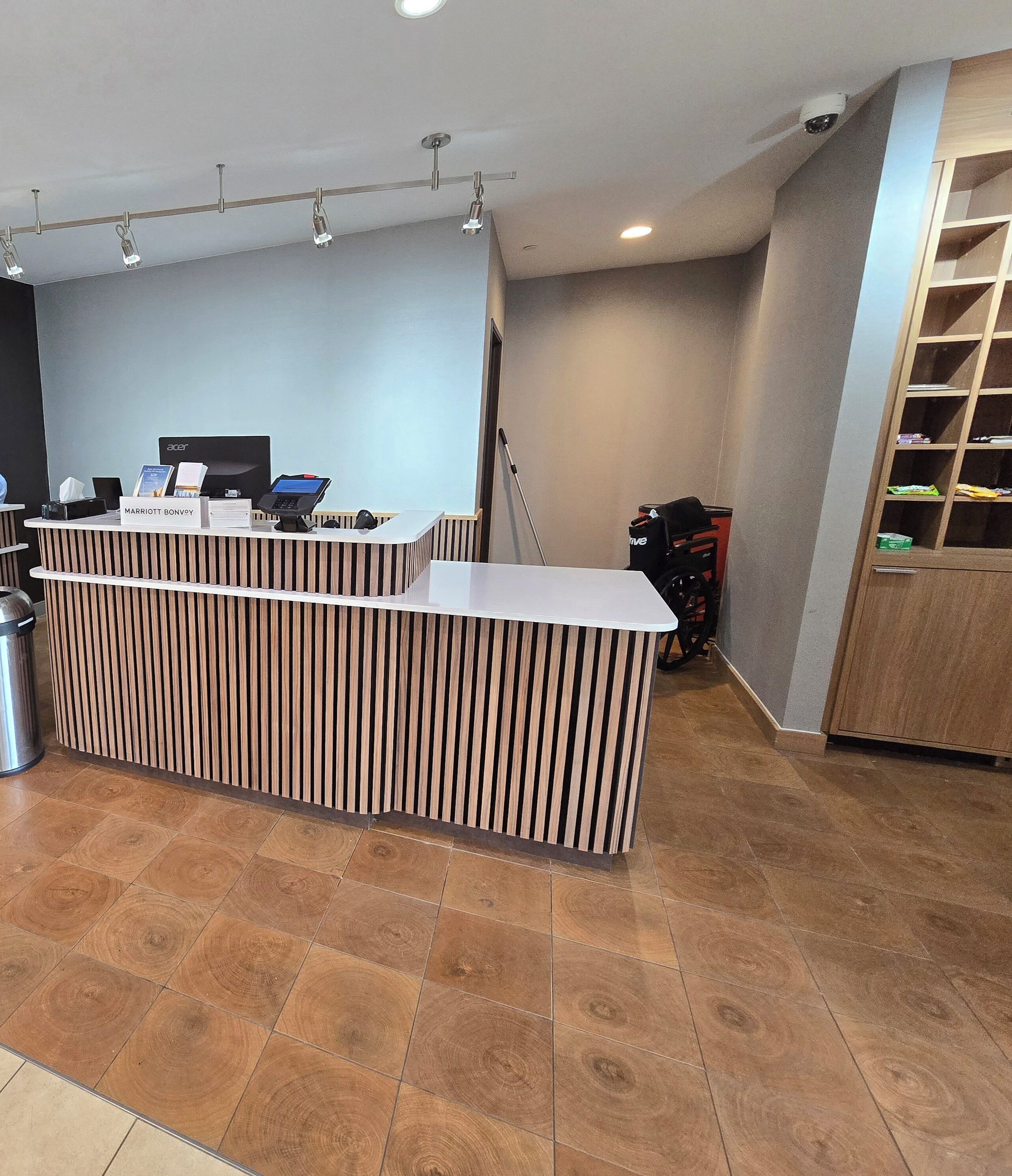 Un mostrador de recepción de diseño moderno, un cubo de basura y una silla de ruedas al fondo.