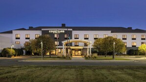 Et Courtyard hotel med moderne design, med en central indgang og en overdækket gang, mange vinduer samt en velplejet græsplæde.