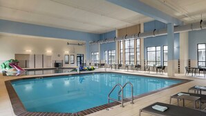 En indendørs swimmingpool med rutsjebane, liggestole og borde.