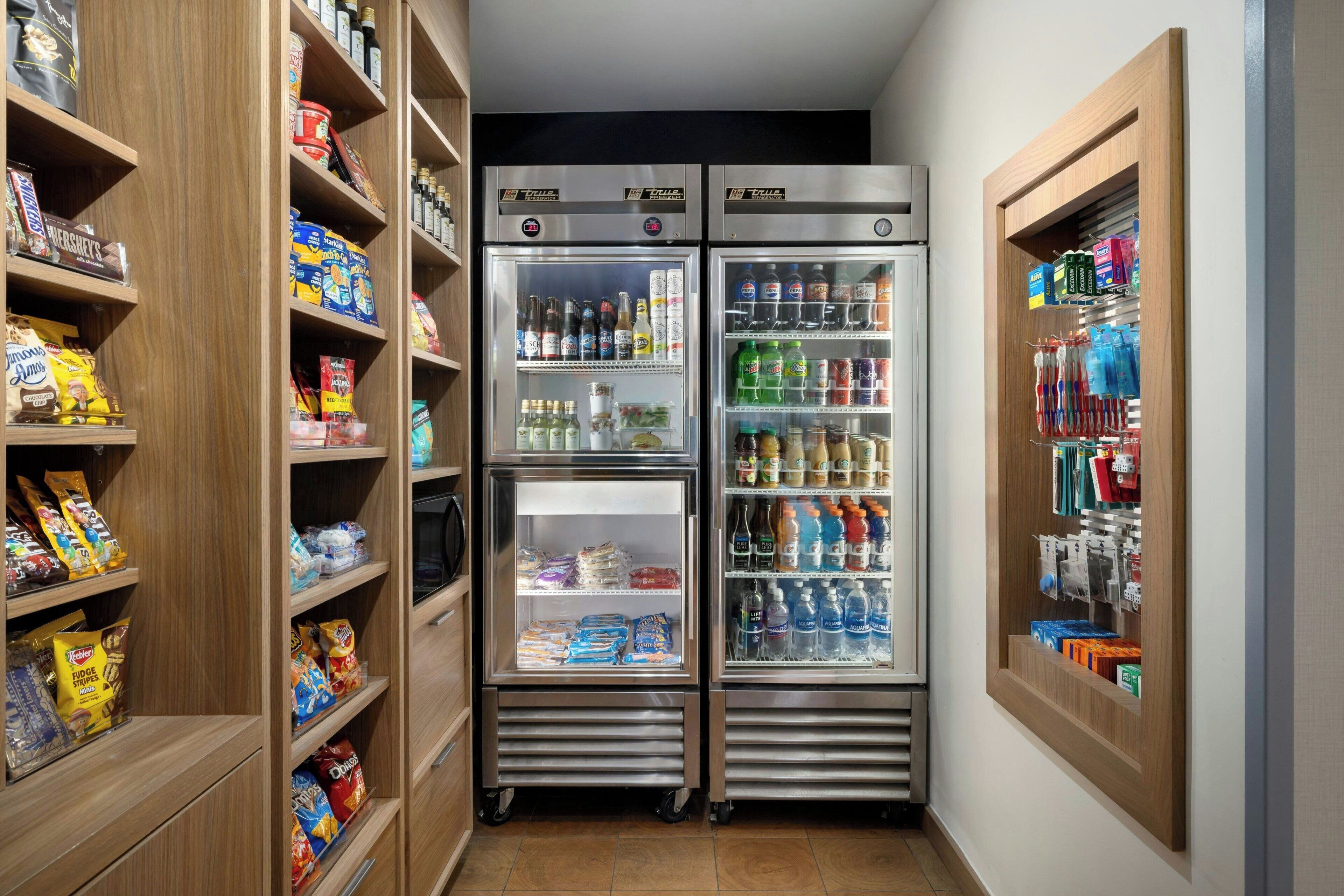 Un corridoio stretto con due vetrine refrigerate su entrambi i lati, piene di snack, bevande e altri prodotti alimentari.