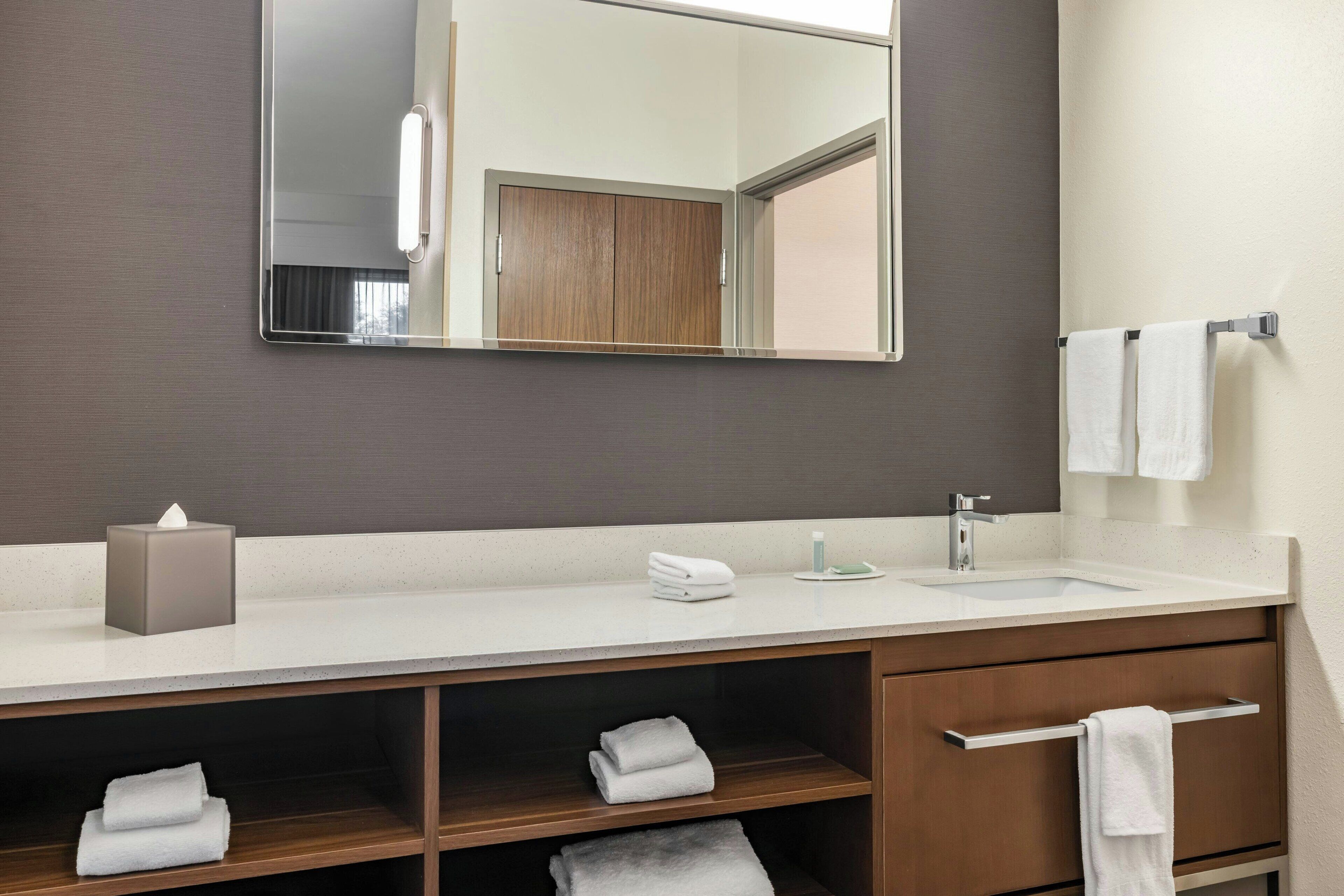 Un baño moderno con un espejo grande, un lavabo y un mueble de tocador con un perchero para toallas.