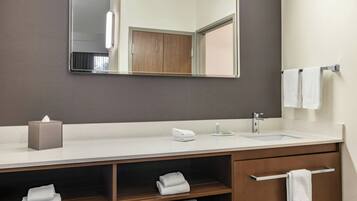 Un baño moderno con un espejo grande, un lavabo y un mueble de tocador con un perchero para toallas.