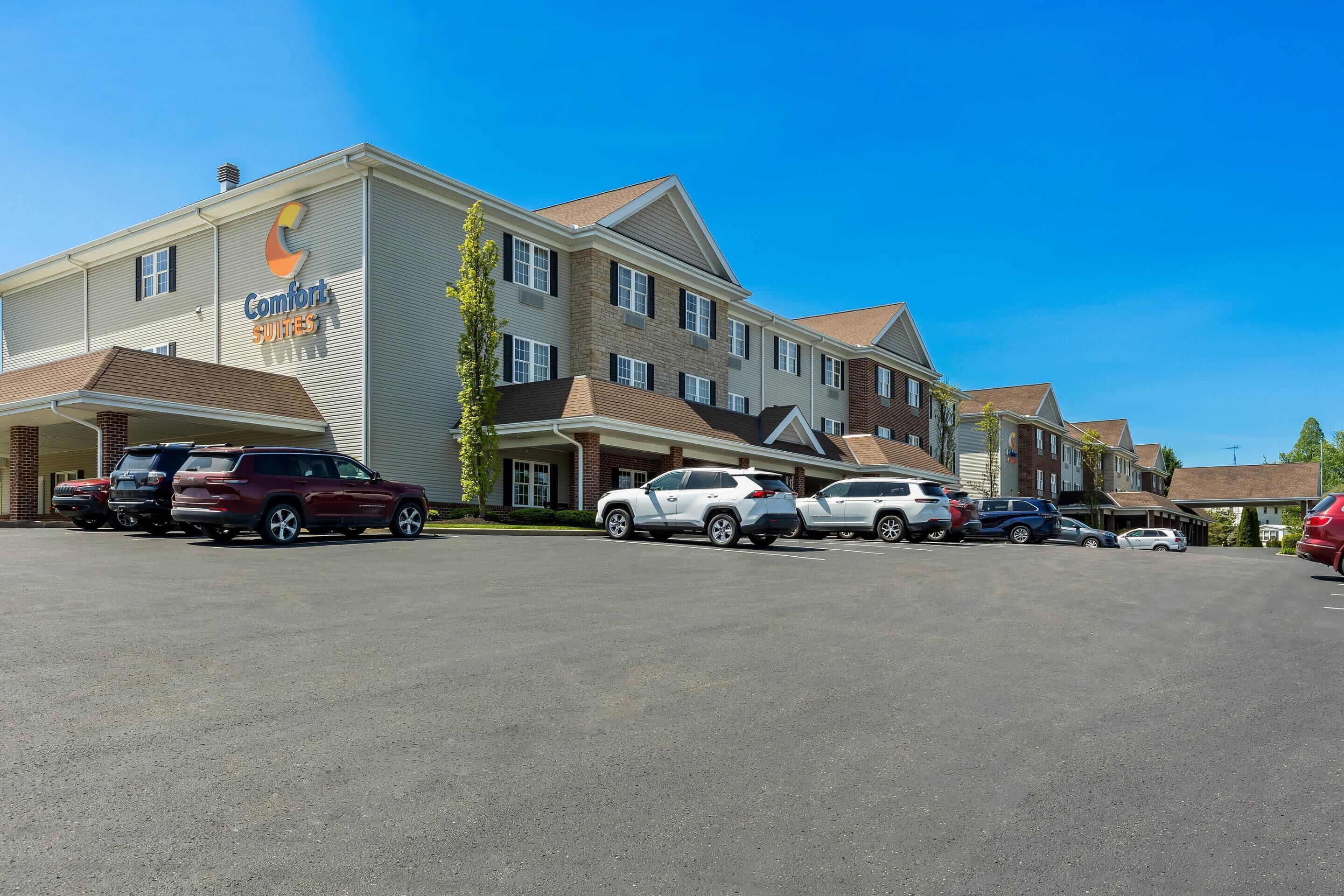 Hotel med parkeringsplads, flere store jeeps parkeret, og en klar blå himmel.