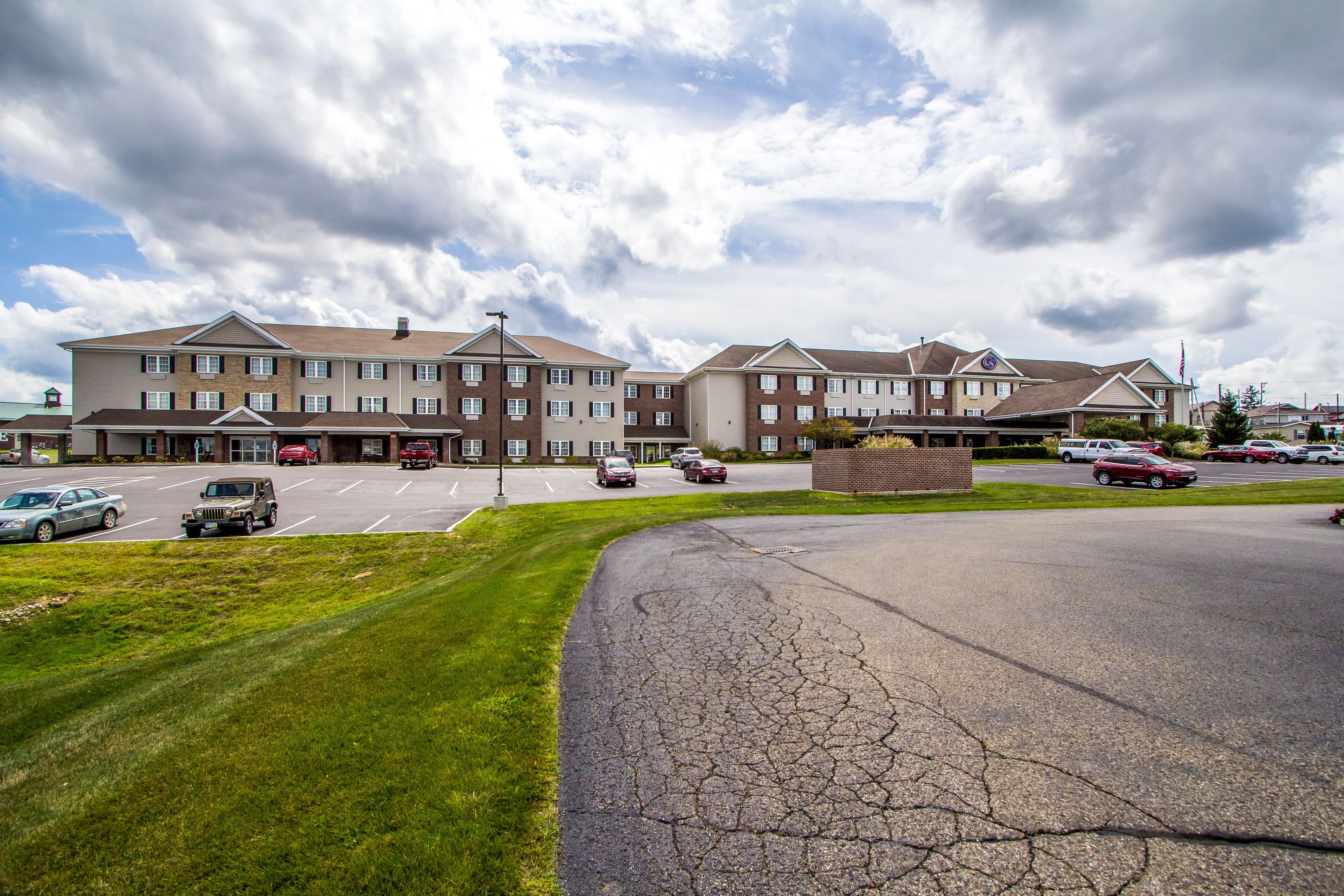 A multi-story hotel with a parking lot and a grassy area.