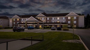 A multi-story hotel with a parking lot, a covered entrance, and a well-maintained lawn.