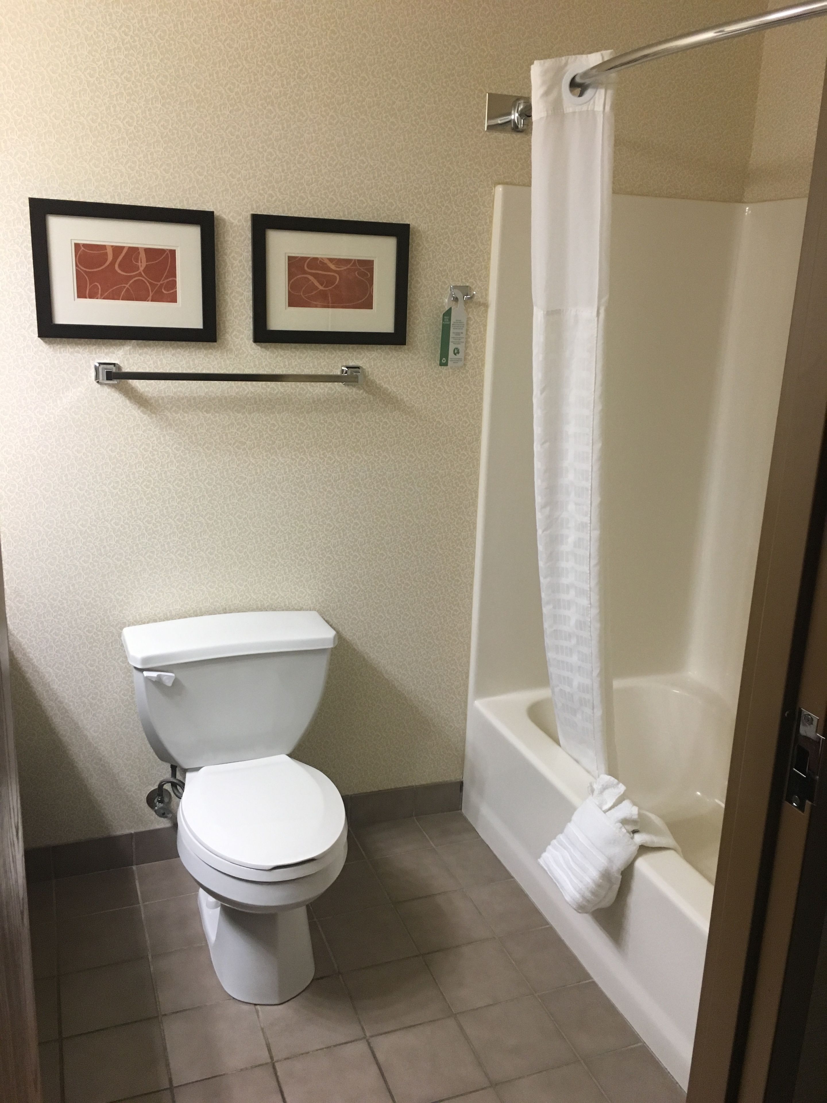 Une salle de bain avec des toilettes, une baignoire et deux tableaux encadrés au mur.