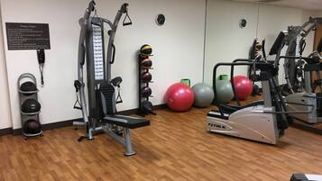 A fitness center with exercise equipment, a wall-mounted phone, and a rack of sports balls.