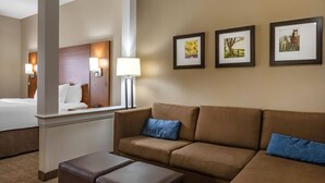 A hotel room with a bed, a sofa, a coffee table, and a wall with framed pictures.