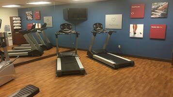 A gym with treadmills, a water cooler, and motivational posters on the wall.