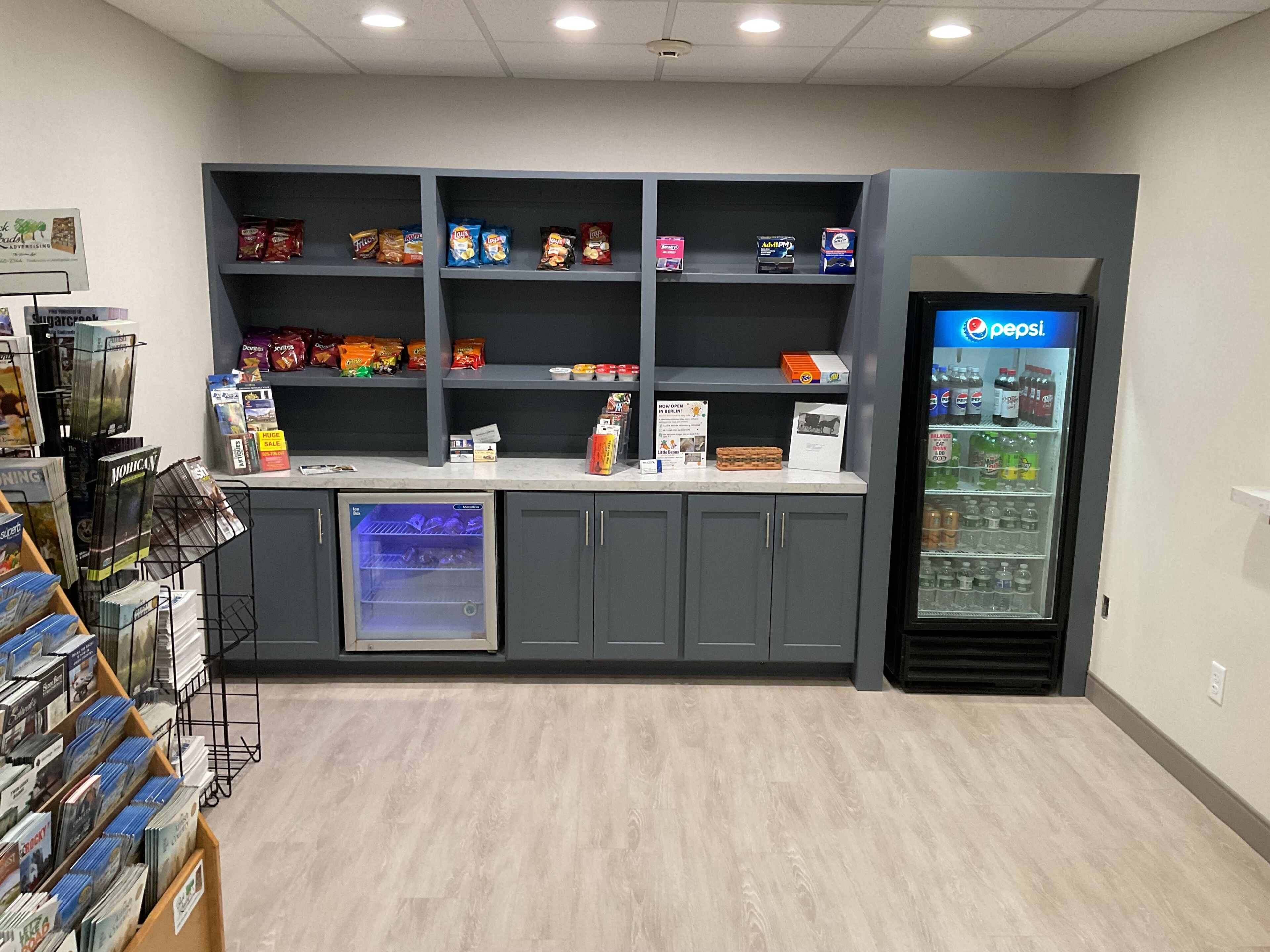 Un bar de aperitivos con estantes llenos de papas fritas y un refrigerador de Pepsi.