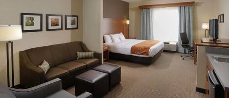 Une chambre d’hôtel avec un lit, un canapé, un bureau, une télévision et une lampe.