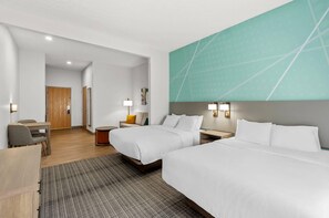 A hotel room with two beds, a desk, a chair, a small table, and a wall-mounted TV. - Comfort Suites Hotel and Conference Center (Berlin)