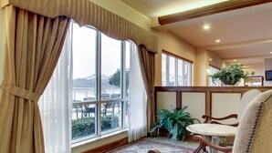 Una habitación con un ventanal grande, una alfombra estampada y una silla de madera.