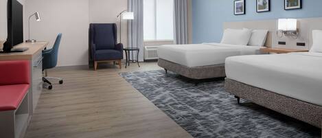 A hotel room with two beds, a desk with a computer, a chair, and a TV.