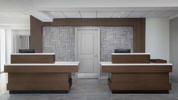 A reception area with two wooden reception desks, a herringbone-patterned wall, and a white door.