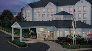 A hotel with a covered entrance, a flagpole, and a landscaped garden.