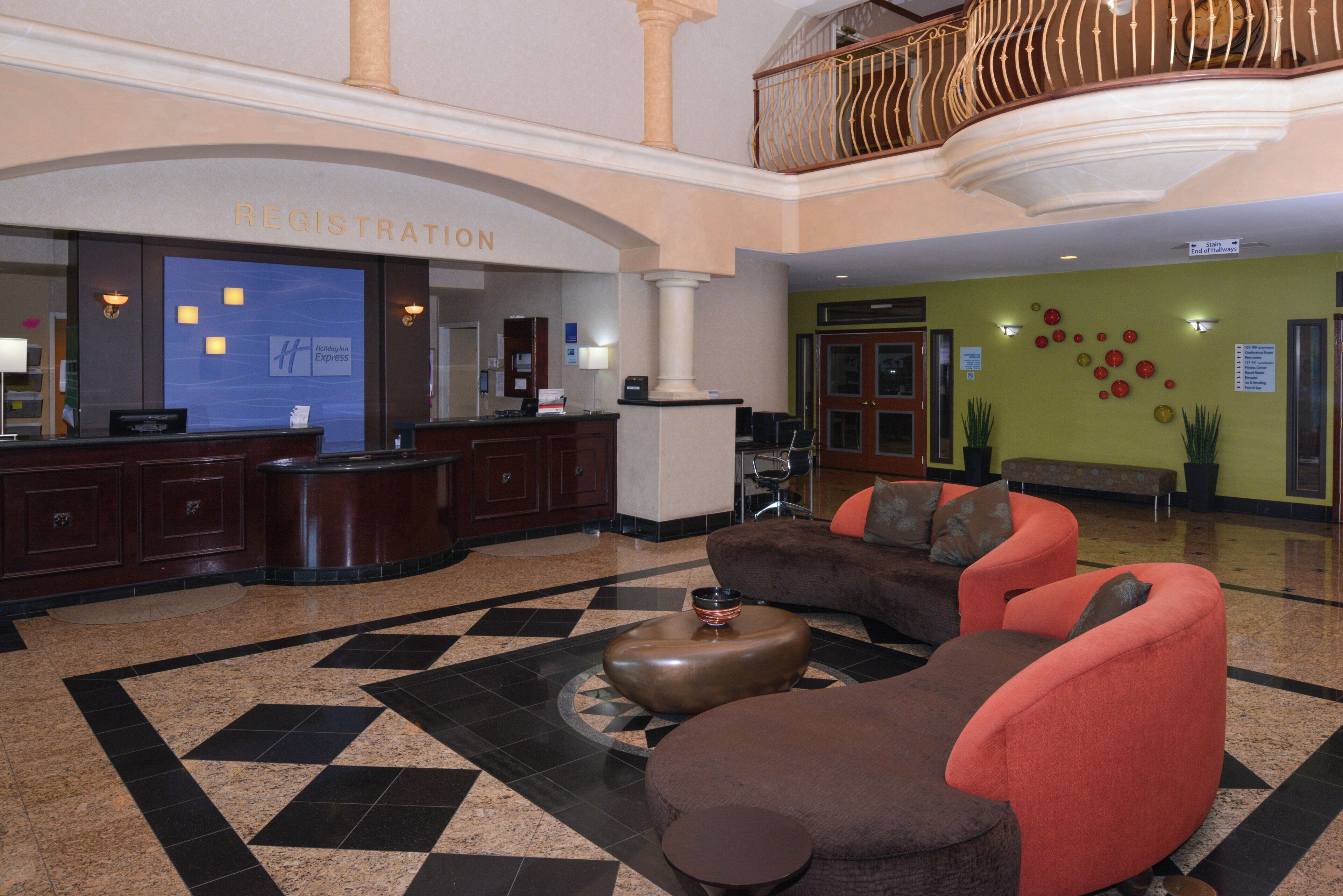 A hotel lobby with a reception desk, seating area, and a staircase.