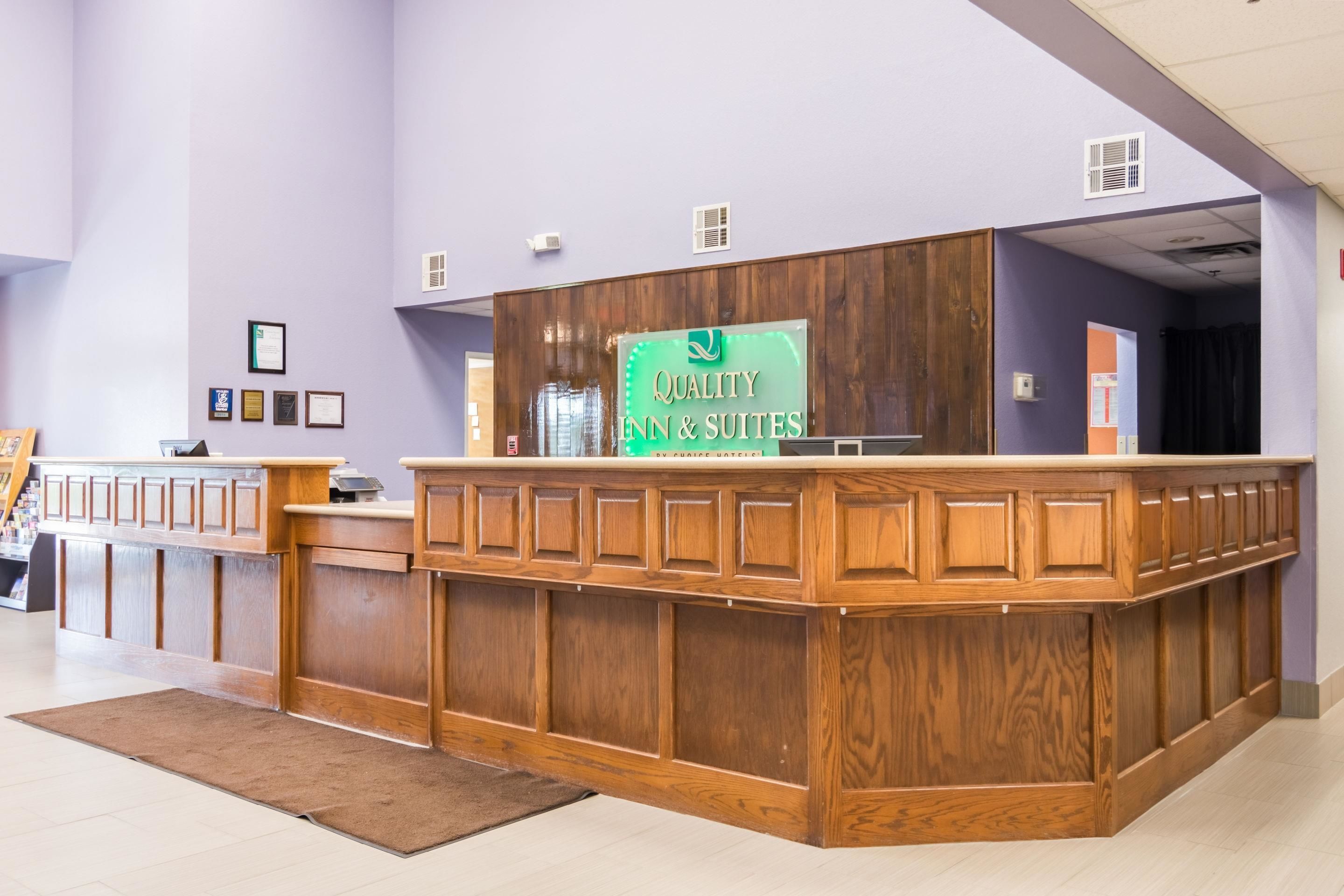 A reception desk with a sign reading "Quality Inn & Suites" and a wooden counter.
