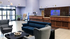 Un hall con mostrador de recepción, un sofá azul, sillones, una mesa de centro y una planta en maceta.