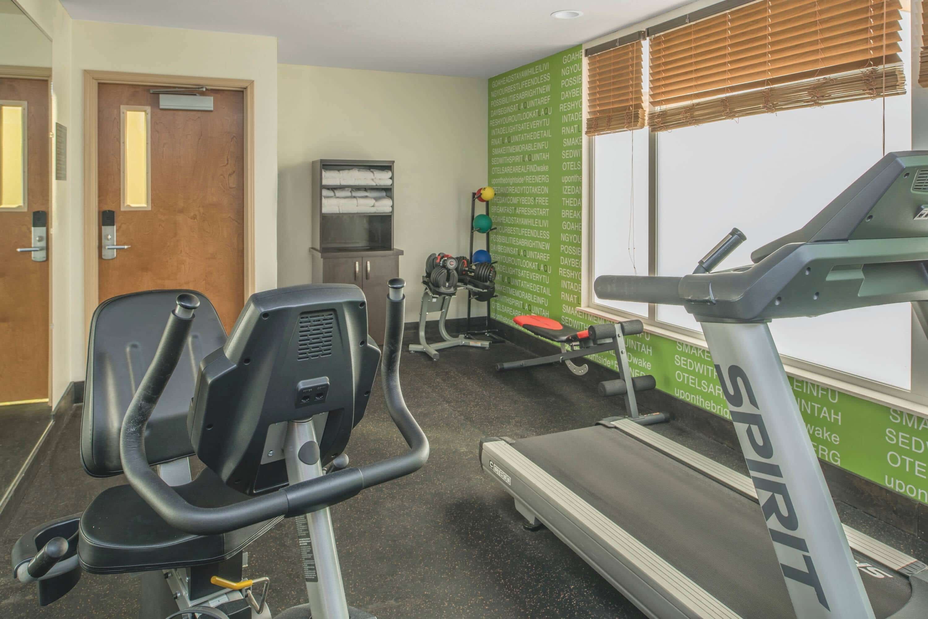 Ein Fitnessstudio mit Trainingsgeräten, darunter ein Laufband, ein Ergometer und Kraftgeräte.